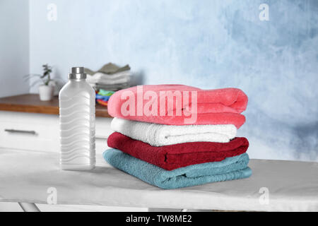 Folded towels and laundry detergent on ironing board Stock Photo