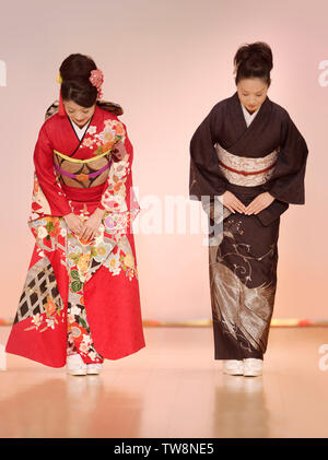 License available at MaximImages.com - Japanese women in elegant red and black kimono bowing at a fashion show in Kyoto, Japan.