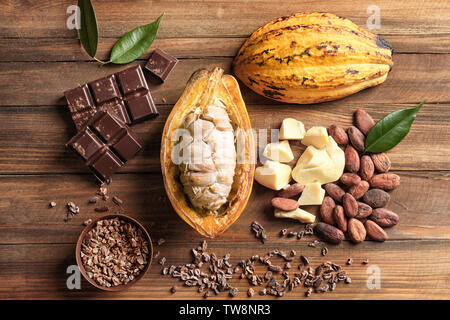 Composition with cocoa pod and products on wooden background, top view Stock Photo