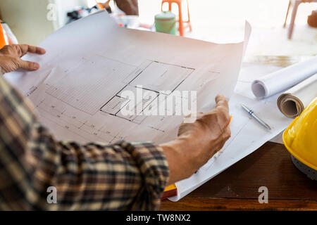 Engineer or foreman with blueprint in building construction site Stock Photo