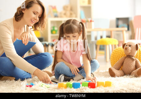 Female psychologist with cute little girl during play therapy Stock Photo