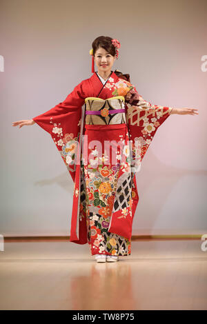 License and prints at MaximImages.com - Young Japanese woman in a beautiful bright red kimono with a colorful floral pattern, golden obi. Japan