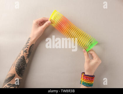 Woman holding rainbow slinky on grey background, top view Stock Photo