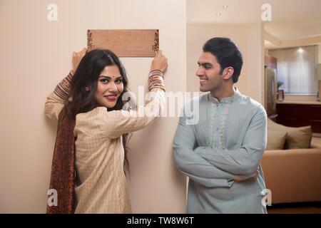 Young couple newlywed in traditional dress placing name plate to home Stock Photo