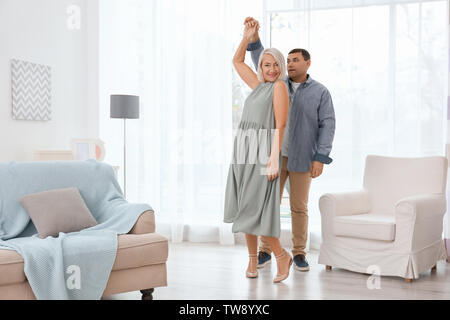 Adorable mature couple dancing together in living room Stock Photo