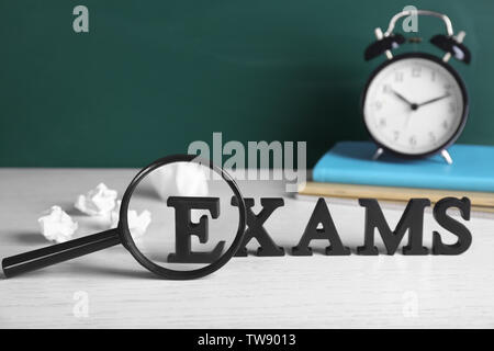 Word EXAMS made of letters and magnifying glass on wooden table Stock Photo