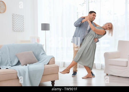Adorable mature couple dancing together in living room Stock Photo