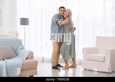 Adorable mature couple dancing together in living room Stock Photo
