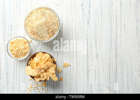 Dried garlic flakes, granules and powder in bowls on wooden background Stock Photo