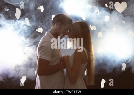 Young loving couple on dark background with backlit and smoke Stock Photo