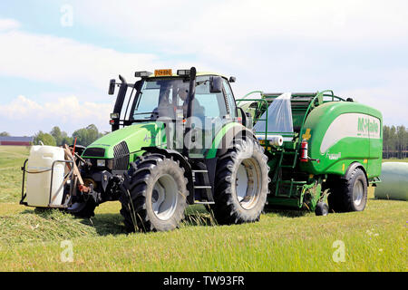 Salo, Finland. June 15, 2019. Farmer working with Deutz-Fahr Agrotron tractor and McHale 3 plus integrated baler wrapper in hay field on day of summer Stock Photo
