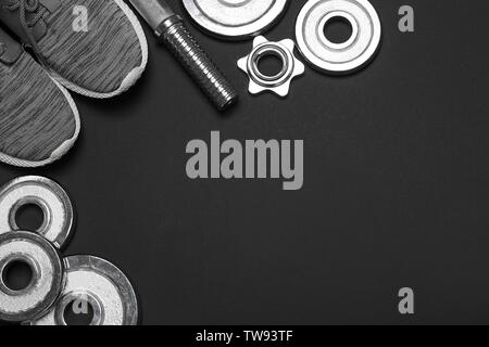 Weight plates, sneakers and blank space for gym exercise plan on dark background. Flat lay composition Stock Photo