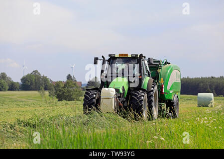 Salo, Finland. June 15, 2019. Farmer working with Deutz-Fahr Agrotron tractor and McHale 3 plus integrated baler wrapper in hay field on day of summer Stock Photo