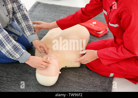 Woman practicing CPR on mannequin in first aid class Stock Photo