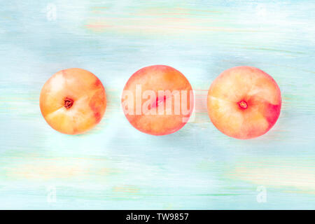 An overhead photo of vibrant organic flat saturn peaches, shot from above on a teal background with copy space Stock Photo