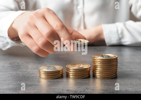 Woman stacking golden bitcoins on table, closeup Stock Photo