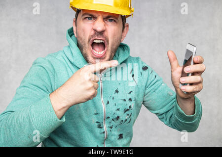 construction supervisor is shouting to a cell phone, pointing with his finger Stock Photo
