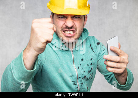 The building supervisor is shouting to a cell phone, front view Stock Photo