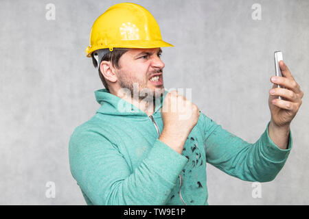 The building supervisor is shouting to a cell phone, side view Stock Photo