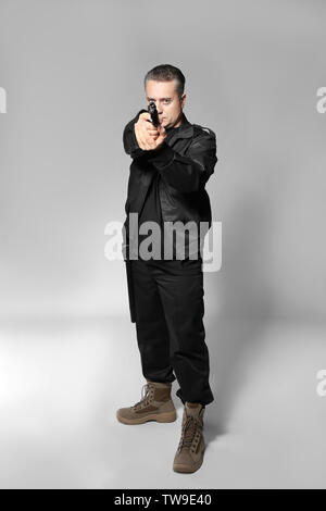 Male security guard with handgun on grey background Stock Photo