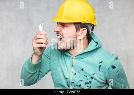 The building supervisor is shouting to a cell phone Stock Photo