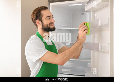 Man cleaning empty refrigerator in kitchen Stock Photo