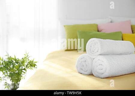 Rolled white towels on bed Stock Photo