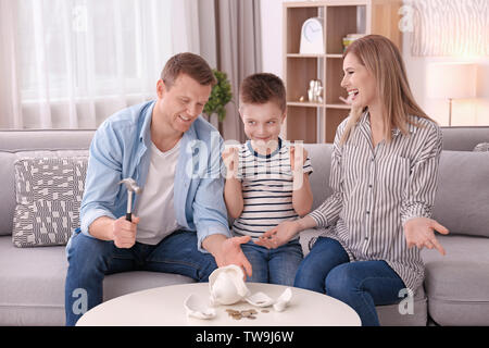 Happy family breaking piggy bank with hammer at home Stock Photo