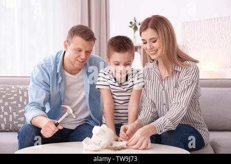 Happy family breaking piggy bank with hammer at home Stock Photo