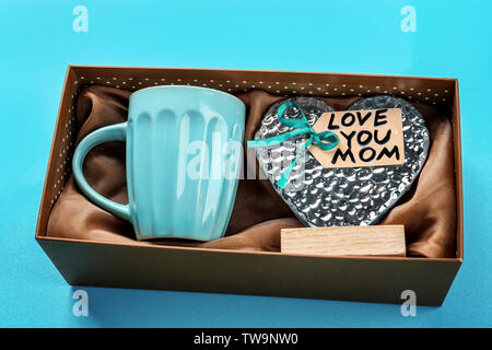 https://l450v.alamy.com/450v/tw9nw0/gift-box-with-cup-and-heart-figure-on-color-background-mothers-day-celebration-tw9nw0.jpg