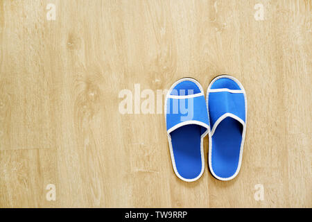 Pair of Blank Blue House Slippers Isolated from Hotel. Woman Bed Shoes, Clear Warm Sandal Over Wood at Bedroom. Soft Comfortable Home Footwear on Wood Stock Photo