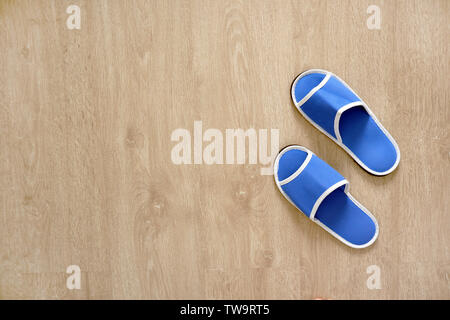 Pair of Blank Blue House Slippers Isolated from Hotel. Woman Bed Shoes, Clear Warm Sandal Over Wood at Bedroom. Soft Comfortable Home Footwear on Wood Stock Photo