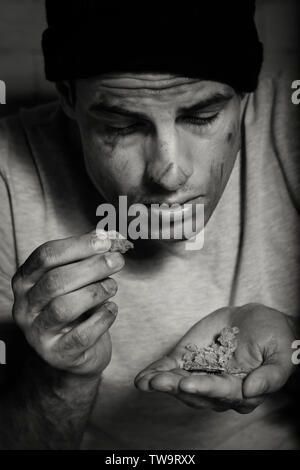 Hungry poor man eating piece of bread Stock Photo