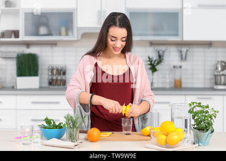 Young woman preparing tasty lemonade in kitchen Stock Photo