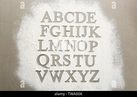 Silhouettes of alphabet letters on scattered flour Stock Photo