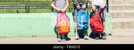 Children of different ages, boys and girls are holding bright backpacks. School concept. Horizontal frame. Copy space Stock Photo