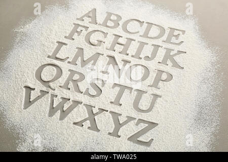 Silhouettes of alphabet letters on scattered flour Stock Photo