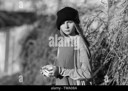 Homeless poor teenage girl holding empty bowl outdoors Stock Photo