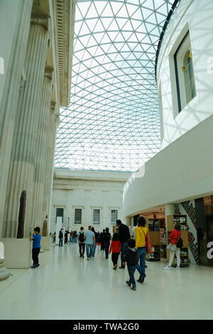 A family and people walk past a shop in the Queen Elizabeth II Great Court in the British Museum in London, United Kingdom.