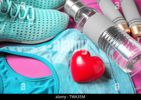 Gym stuff and red heart on color background. Cardio training concept Stock Photo