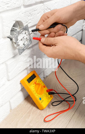 Electrician measuring voltage of socket Stock Photo