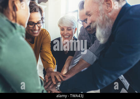 Business colleagues putting their hands together in office. Business people making pile of hands. Stock Photo