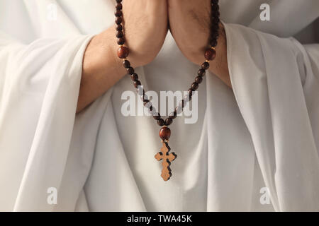 Praying monk with rosary beads, closeup Stock Photo