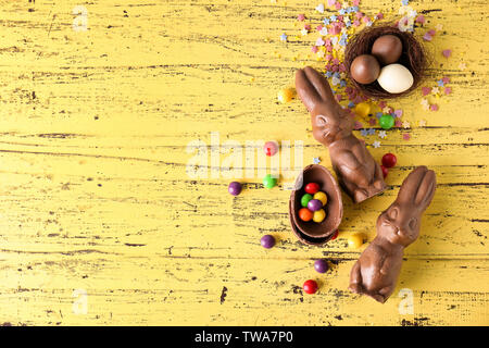 Chocolate Easter bunnies and candies on wooden background Stock Photo