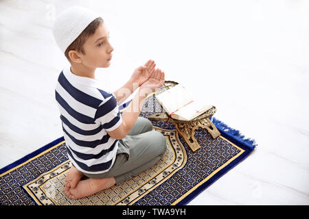 Muslim boy praying on rug at home Stock Photo
