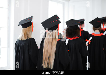 Students in bachelor robes and mortarboards indoors. Graduation day Stock Photo