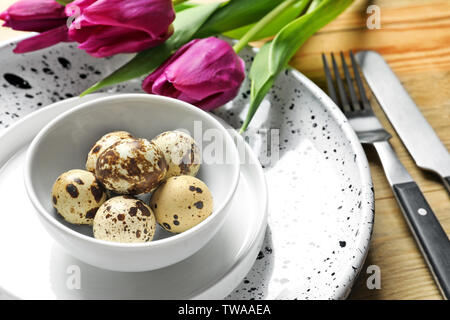 Beautiful festive Easter table setting with quail eggs and tulips, closeup Stock Photo