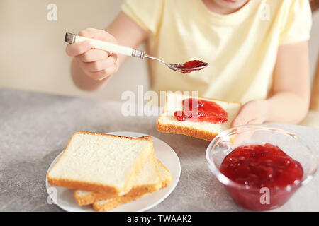 Little girl spreading jam on toast at home Stock Photo