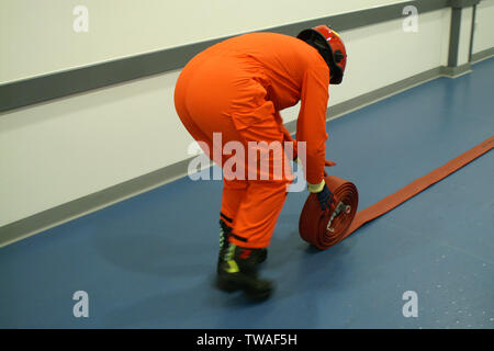 fire fighter rolling up fire hose Stock Photo