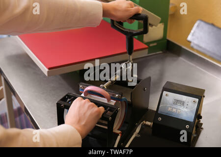 Young woman printing on cup at workshop Stock Photo